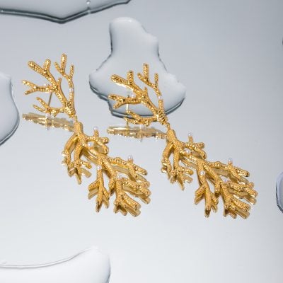 Exquisite gold coral-inspired earrings adorned with pearls, displayed on a sleek reflective surface. These statement jewelry pieces combine luxury with style, ideal for enhancing elegant looks.