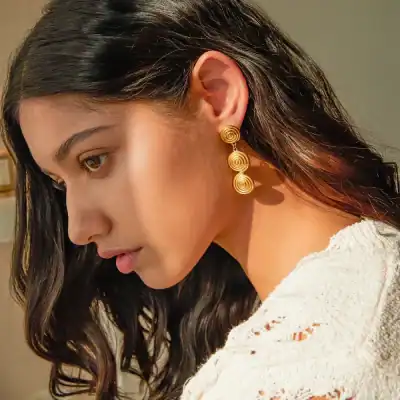 Close-up of woman wearing gold spiral earrings, showcasing trendy and luxurious jewelry from Monalisa Store for sophisticated style and accessorizing.