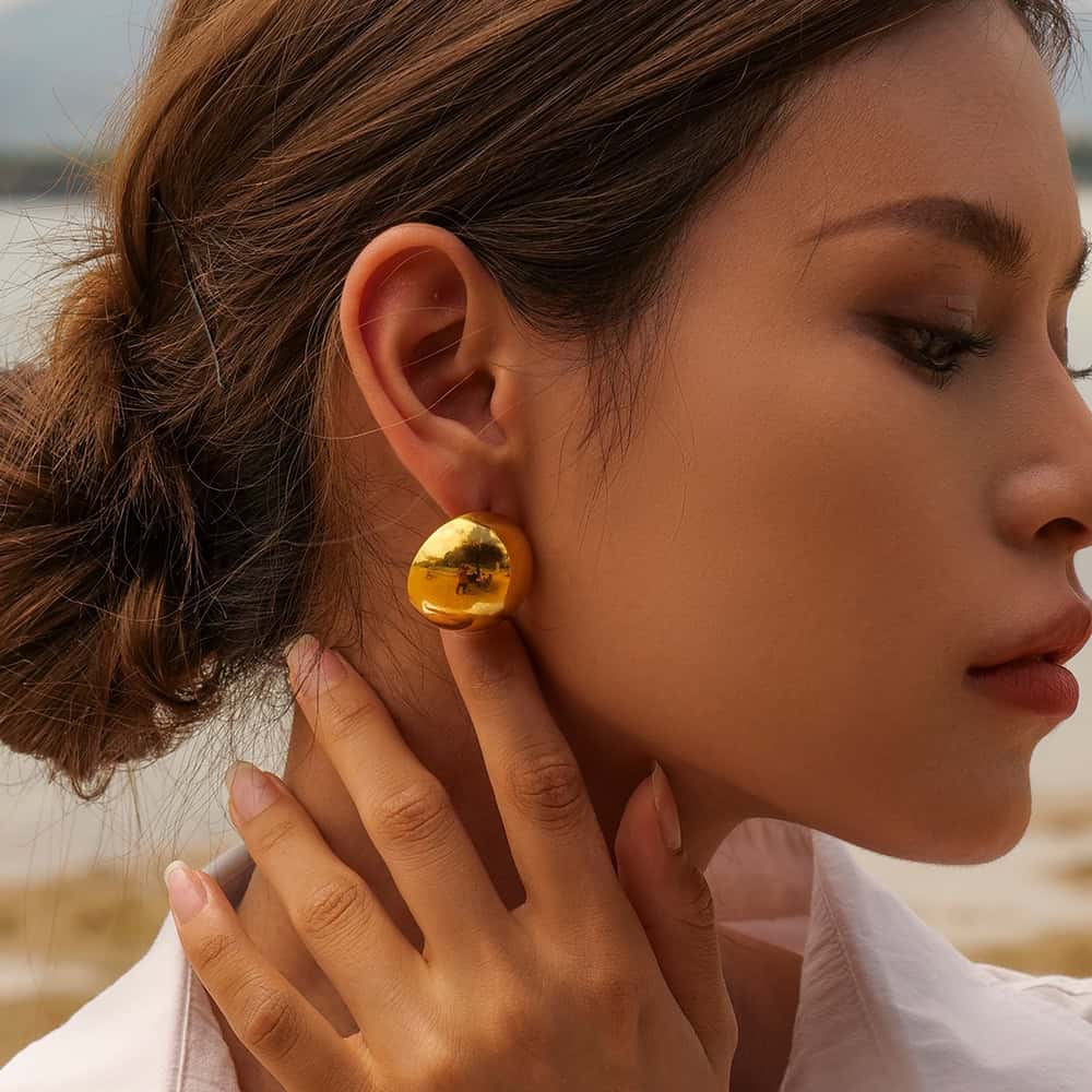 Close-up of a woman wearing luxurious gold statement earrings, showcasing high-end jewelry style for women, perfect for fashion accessory shopping at Monalisa Store.
