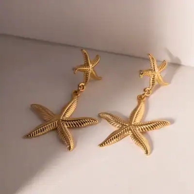 Elegant gold starfish earrings, perfect for beach-inspired or summer jewelry collections, featuring detailed textured design.