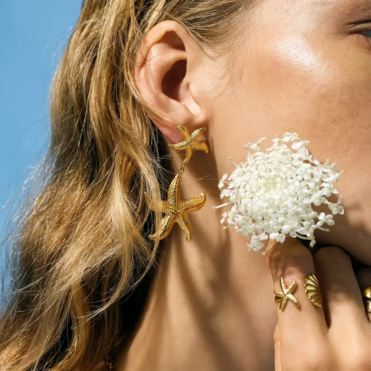 Close-up image of a woman wearing gold starfish earrings and matching rings, showcasing stylish accessories for women at Monalisa Store, perfect for enhancing photographs for jewelry and fashion brands.