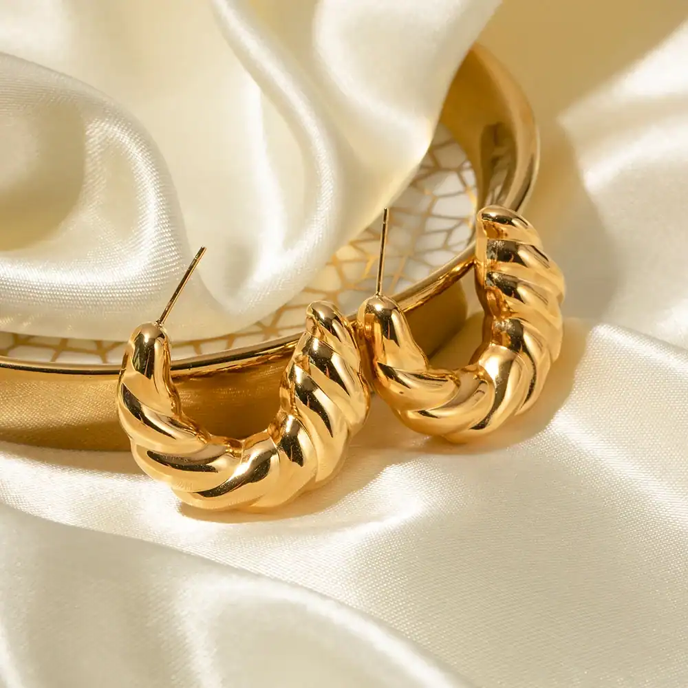 Elegant gold hoop earrings with twisted design showcased on satin fabric, perfect for stylish accessories, available at Monalisa Store.