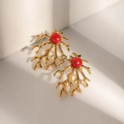 Bright gold coral-shaped earrings featuring striking red beads, perfect for stylish accessorizing and adding a touch of elegance to your outfit.