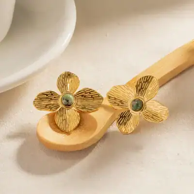 Elegant gold flower earrings with green gemstone center, perfect for stylish accessories and luxury jewelry collections.