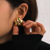 Close-up of a stylish gold flower-shaped earring worn by a woman, showcasing luxury jewelry and modern fashion accessories for eye-catching style.
