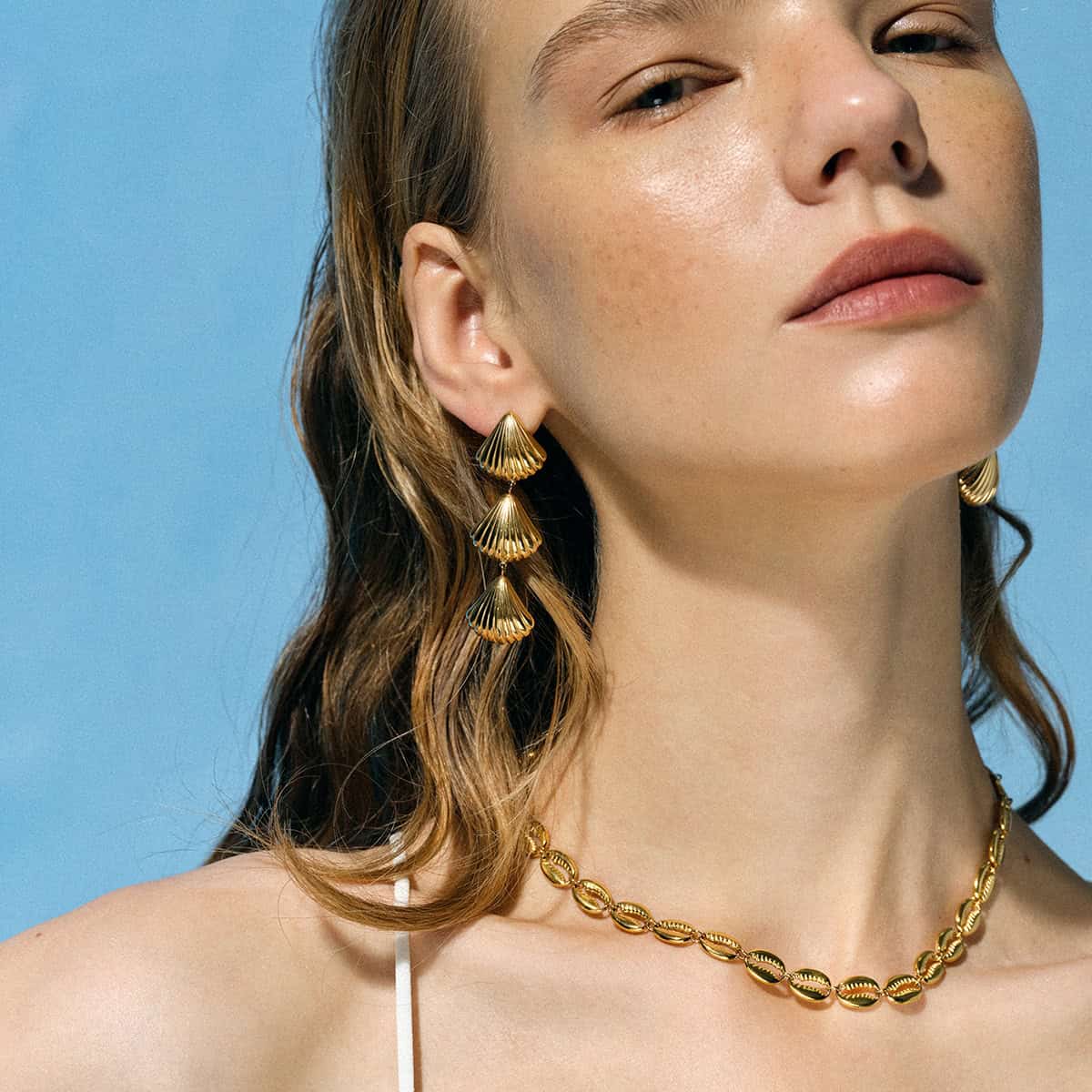 Shiny gold shell earrings and matching necklace displayed on a woman, showcasing stylish jewelry for women, perfect for fashion accessories, jewelry lovers, and enhancing personal style.