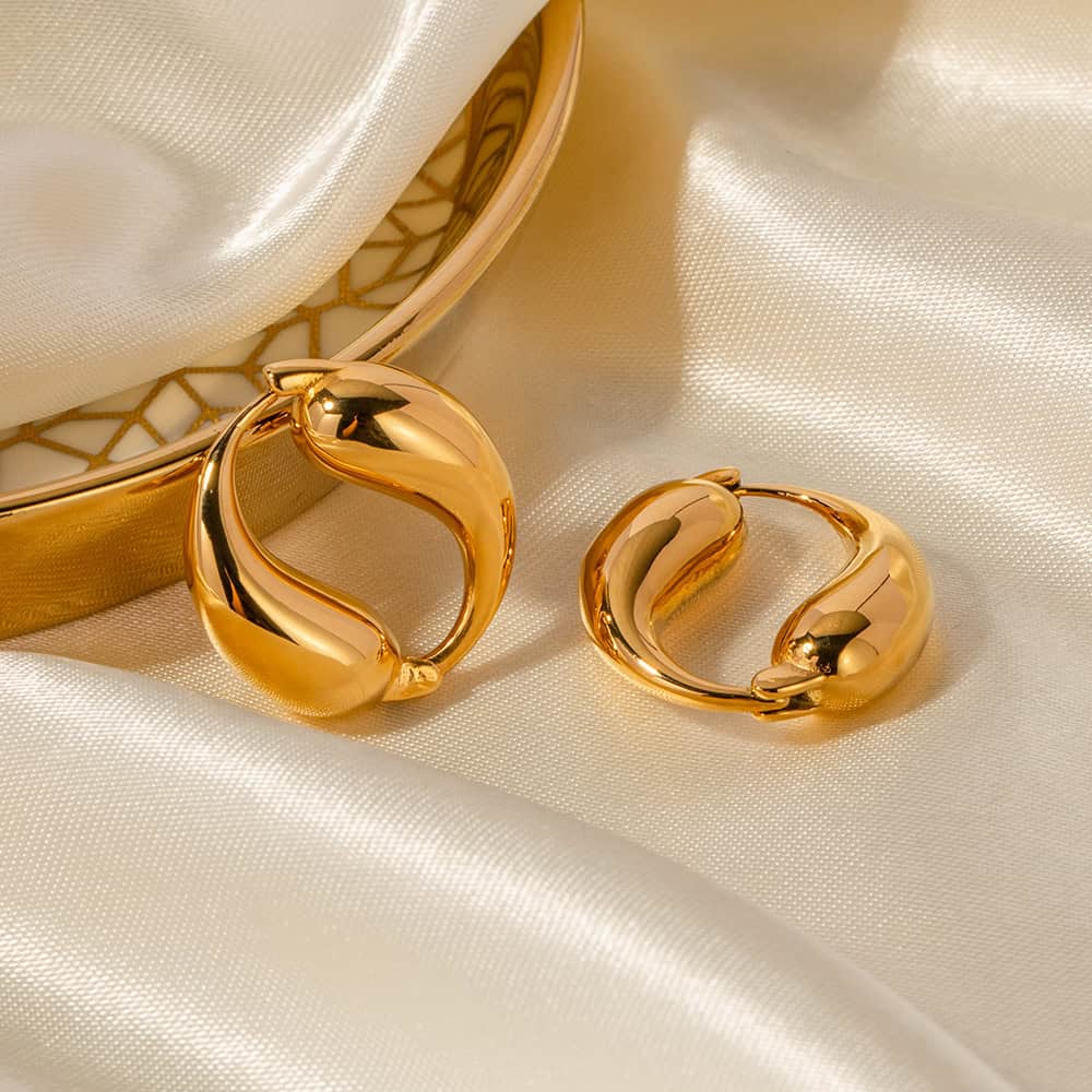 Shiny gold hoop earrings featuring a sleek, modern design with smooth curves, ideal for elegant fashion statements and jewelry enthusiasts.