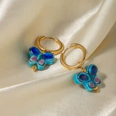 Bright blue and pink butterfly charms hanging from gold hoop earrings, perfect for adding a playful touch to your style.