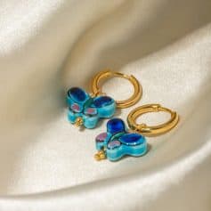 Colorful butterfly-shaped earrings with blue, pink, and black details, featuring gold hoops. Perfect for stylish accessories, offering a vibrant look for any occasion.