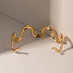 A stylish gold-tone wavy eyeglass holder designed for credit card holders, showcasing luxury and sophistication for sunglasses or optical frames.