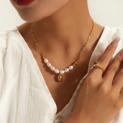 Unique pearl and gold layered necklace with teardrop pendant, stylish gold ring with a large gemstone, perfect for luxury jewelry shopping at Monalisa Store.