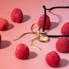 Elegant gold jewelry with raspberry accents, perfect for fashion-forward women and gift ideas. Featuring a unique ribbon-style design, this trendy accessory adds a pop of color to any outfit.