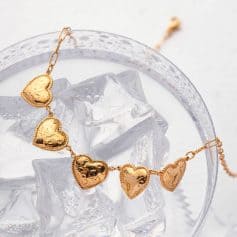 Romantic gold heart necklace perfect for special occasions, featuring shiny, textured hearts on delicate chain. Ideal gift for loved ones or stylish accessory for any outfit.