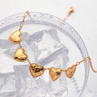 Romantic gold heart necklace perfect for special occasions, featuring shiny, textured hearts on delicate chain. Ideal gift for loved ones or stylish accessory for any outfit.