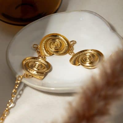 Elegant gold shell jewelry set, spiral pendant necklace and matching earrings, perfect for fashionable accessories and special occasions.