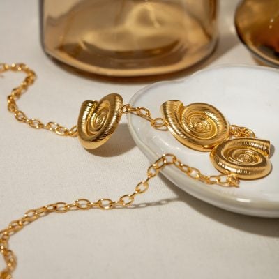 Elegant gold jewelry set with spiral design, perfect for statement accessories and fashion jewelry lovers, displayed on a white dish for stylish presentation.