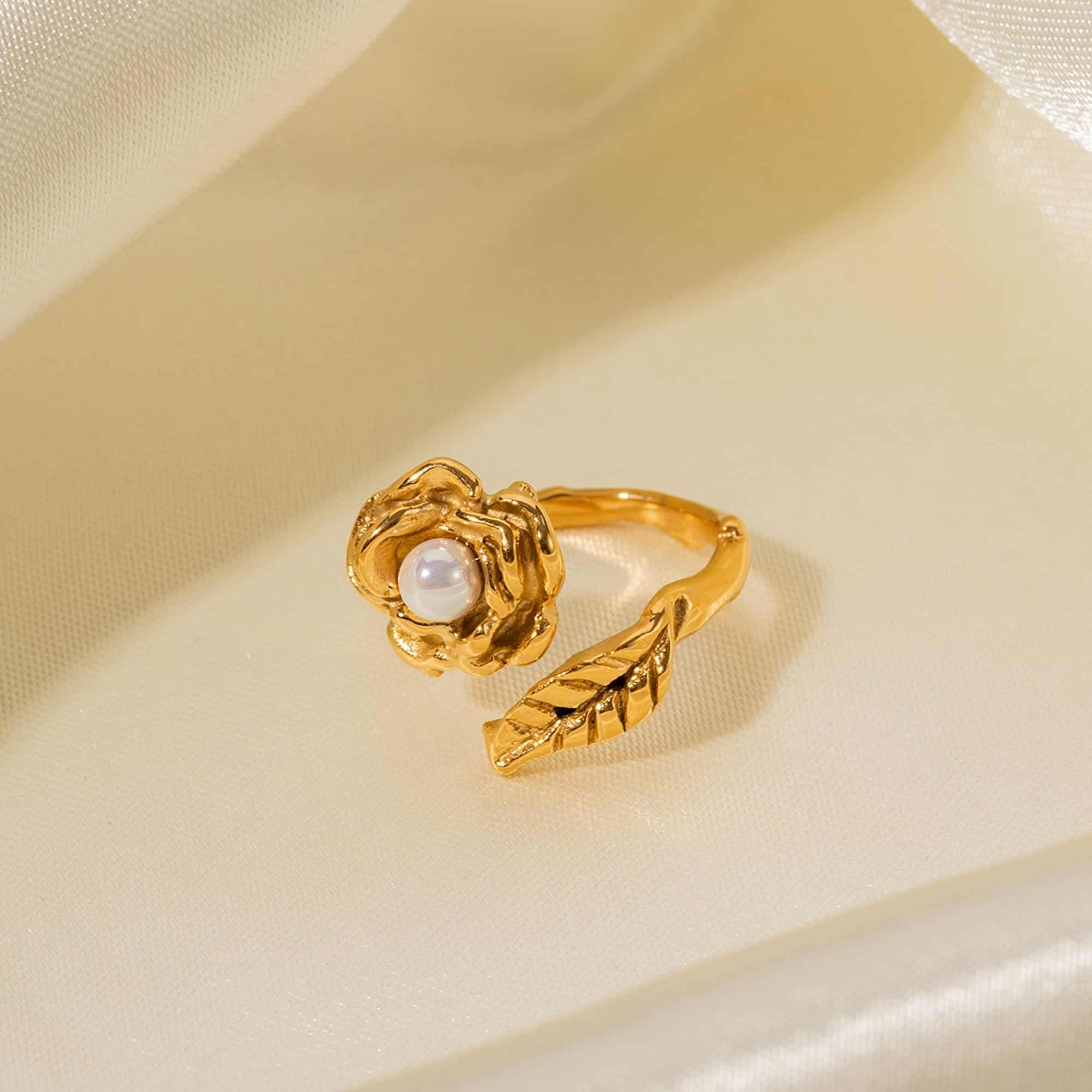 Luxurious gold ring featuring a detailed flower design with a central pearl and a matching leaf-shaped band, ideal for sophisticated jewelry lovers.