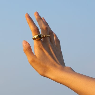 Close-up of a hand wearing elegant gold rings, featuring black gemstone accents, showcasing fashionable jewelry at Monalisa Store for stylish accessories.