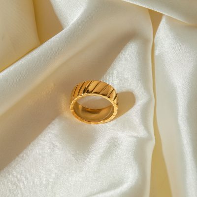 Luxurious gold ring with a textured, modern design displayed on silky satin fabric, ideal for fashion and jewelry enthusiasts.