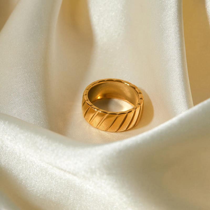 Luxury gold ring displayed on satin fabric with intricate design, perfect for premium jewelry collections.