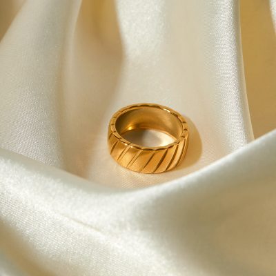 Elegant gold men's ring displaying sleek diagonal engraving, crafted for men's jewelry collection, showcased on soft satin fabric for a premium look.