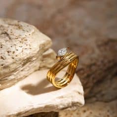 Luxurious gold ring featuring a sparkling diamond set on a textured band, perfect for special occasions or daily elegance.