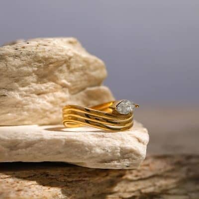 A stunning gold engagement ring featuring a sparkling diamond set on a textured surface, perfect for special occasions or everyday luxury.