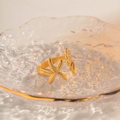 Luxurious gold starfish ring with detailed textured design, crafted for beach lovers and nature-inspired jewelry fans. Perfect accessory for beach outings, summer fashion, or special gifts. Showcased on a sparkling shell for a chic, nautical vibe.