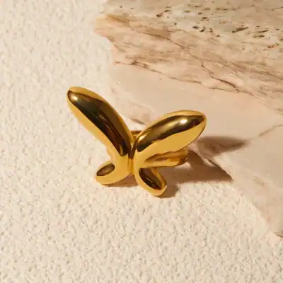 A stunning gold butterfly jewelry ornament placed on a textured surface with a marble accent, perfect for luxury fashion and statement accessories.