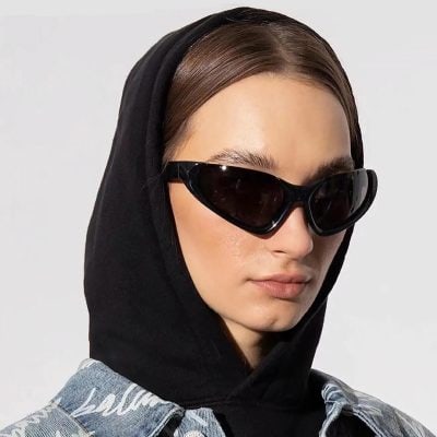 Stylish black sunglasses worn by a woman with a hooded jacket and trendy look.