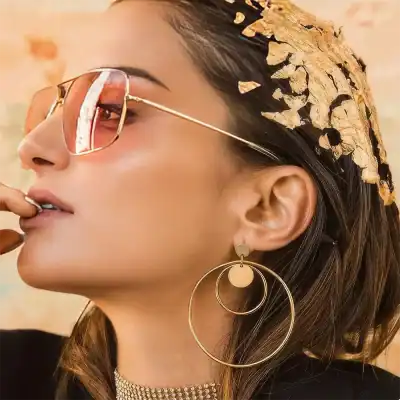Elegant sunglasses, gold hoop earrings, and fashion accessories with a luxurious vibe for modern women.