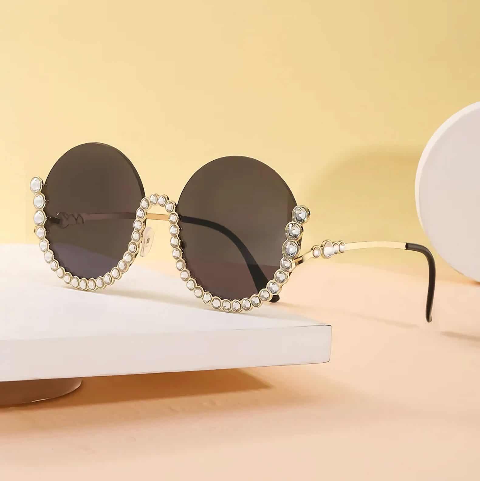 Luxury sunglasses adorned with pearls and rhinestones, featuring dark lenses and stylish gold accents, perfect for a fashionable look.