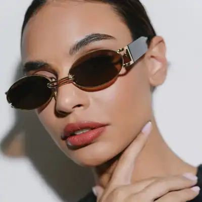 Close-up of a woman wearing stylish oval sunglasses with brown lenses, showcasing trendy optical accessories from Monalisa Store.