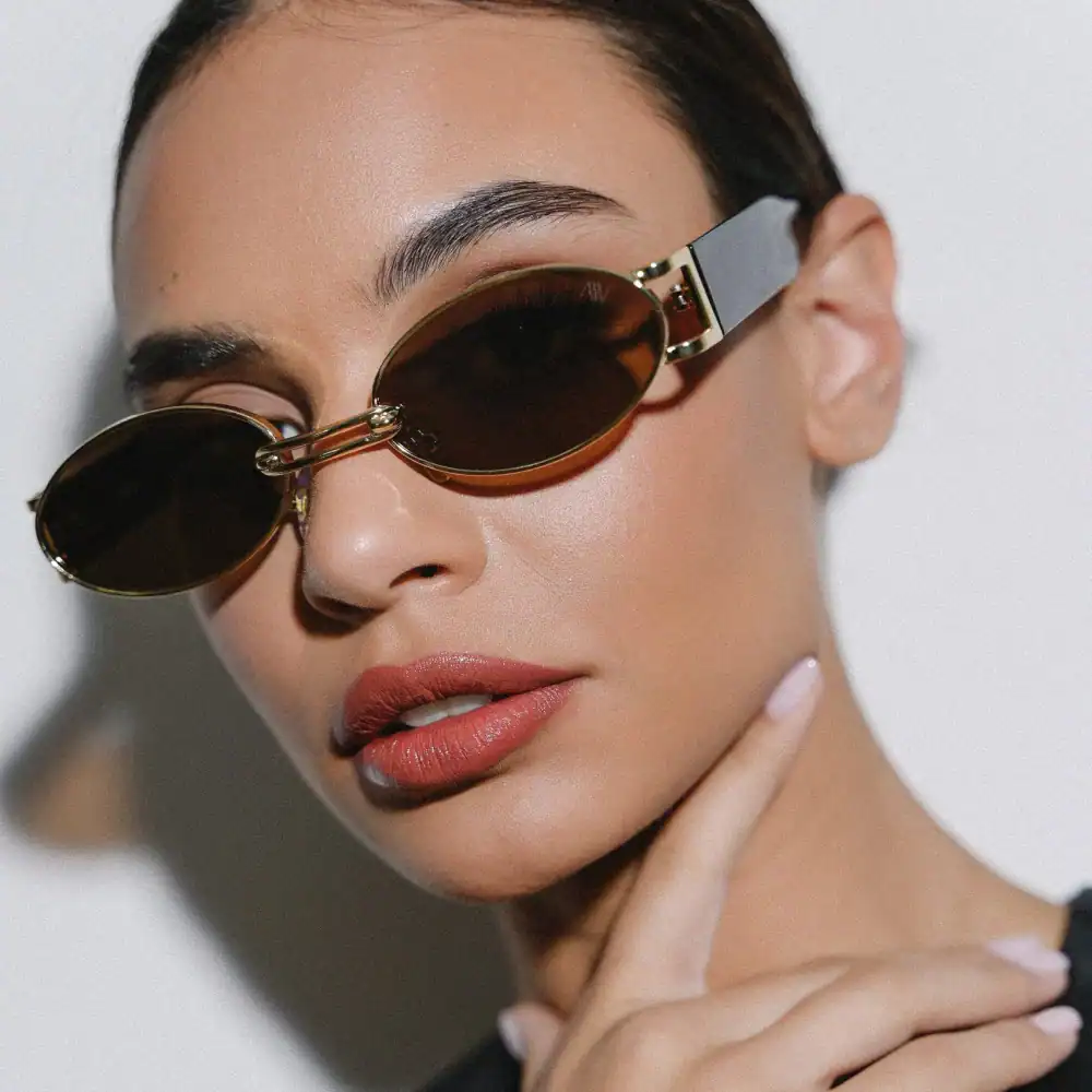 Close-up of a woman wearing stylish oval sunglasses with brown lenses, showcasing trendy optical accessories from Monalisa Store.