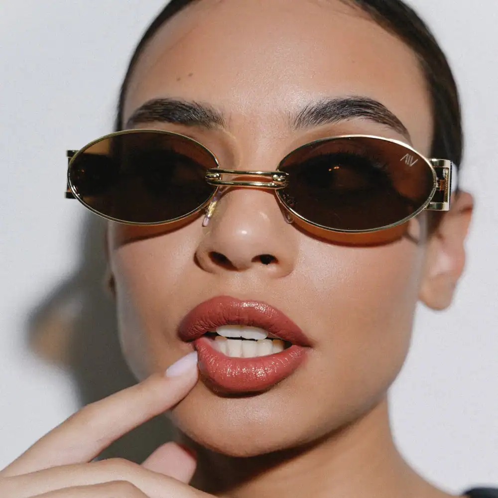 Fashion sunglasses with oval tinted lenses and gold frame, perfect for trendy eye protection.