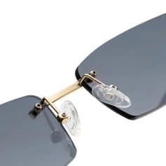 Close-up of modern sunglasses featuring dark tinted lenses, gold-tone metal frame, and clear nose pads, ideal for fashion and eye health.