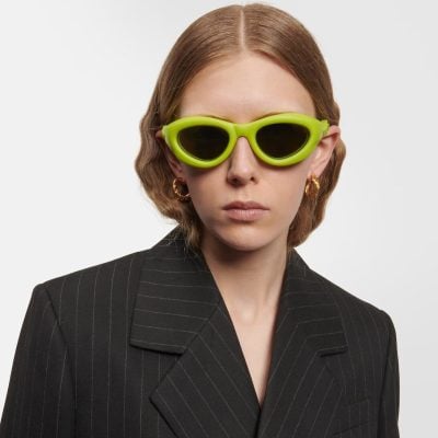 Stylish green sunglasses on a woman with wavy auburn hair.