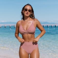 Beautiful woman wearing pink bikini with sunglasses at the seaside for a sunny stylish look.