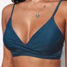 Glamorous blue bikini top with a stylish cut, perfect for swimwear and beach outings, complemented by a delicate gold necklace with a pendant. Enhance your fashion with trendy swimwear accessories.