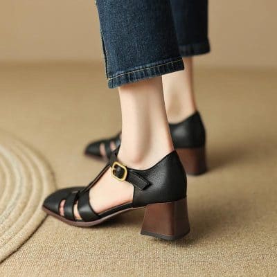 Stylish black leather women’s heels with ankle strap and geometric block heel ideal for parties and formal wear.