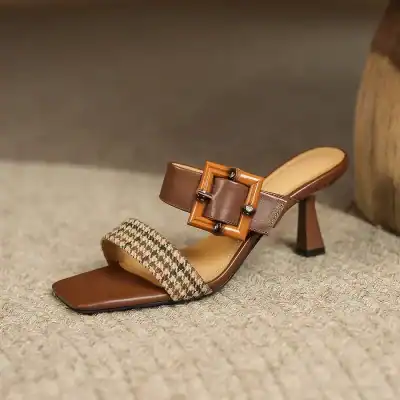 Elegant brown high-heeled sandal with a large decorative buckle, featuring a textured patterned strap and sleek design, perfect for stylish occasions.