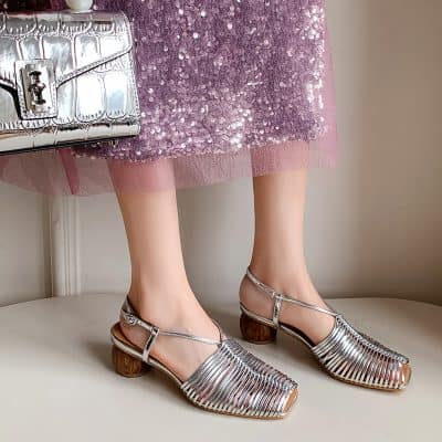 Glamorous silver high-heeled shoes with ankle straps, perfect for special occasions, paired with a pink sequin dress and stylish handbag for a chic, fashionable look.
