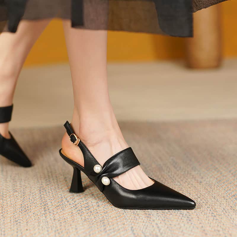 Stylish black women's high heels with pearl accents, featuring a pointed toe, ankle strap, and block heel, ideal for dressy events and fashionable outfits.