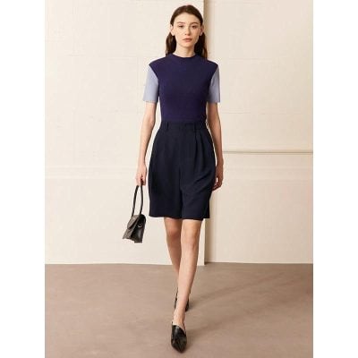 Elegant women's business outfit featuring a navy and purple top with high-waisted navy shorts, black heels, and a stylish handbag, perfect for professional settings and fashion-forward women.