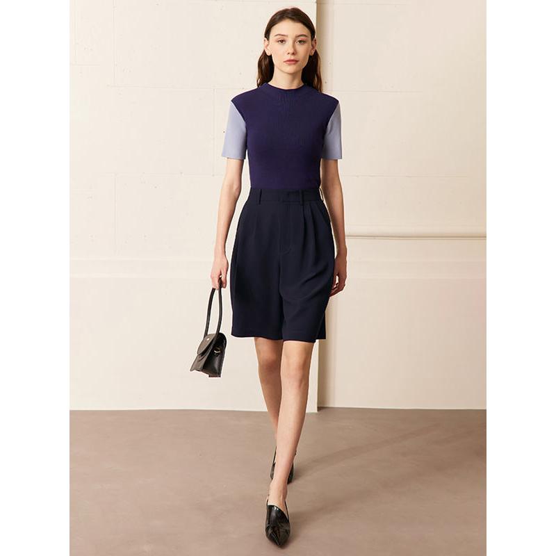 Elegant women's business outfit featuring a navy and purple top with high-waisted navy shorts, black heels, and a stylish handbag, perfect for professional settings and fashion-forward women.