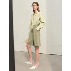 Stylish woman wearing a professional light green blazer and matching knee-length shorts, paired with white heels and glasses, showcasing modern office fashion.