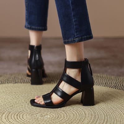Elegant black open-toe high-heeled sandals with strap details, perfect for fashion-forward women. Ideal for accessorizing outfits and making a statement.