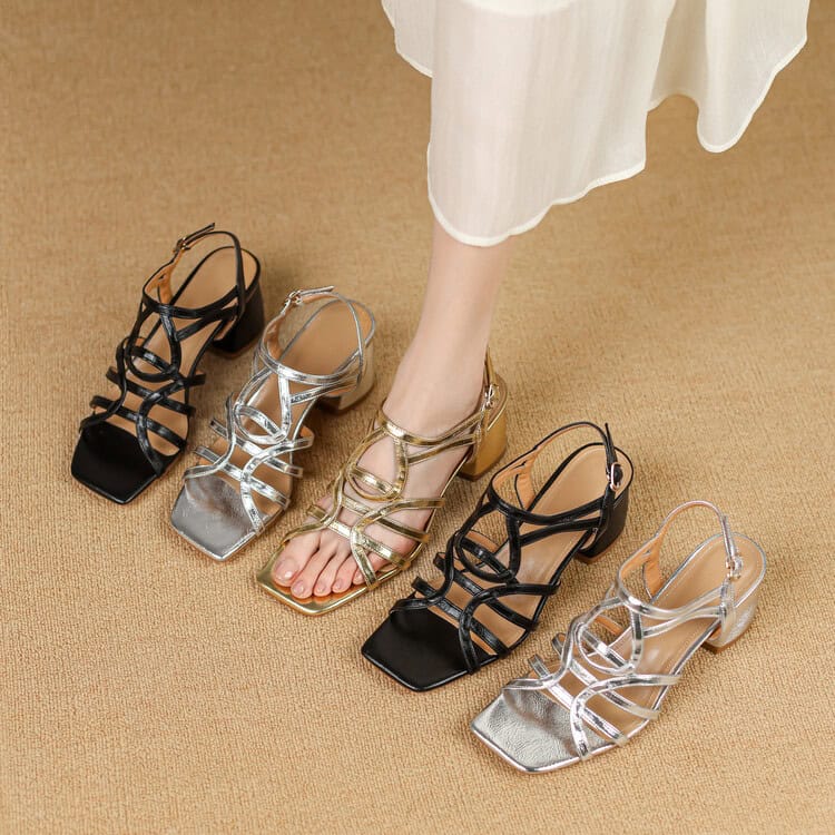 Close-up of elegant women's open-toe high-heeled sandals in black, silver, and gold, displayed on a beige carpet, perfect for fashion-forward footwear shopping at Mona Lisa Store.