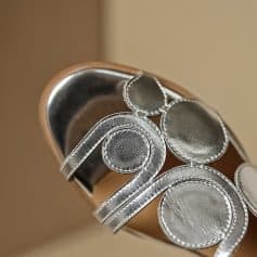 Close-up of a silver jewelry store sign with shiny circular and curved metal elements, representing elegant and stylish jewelry displays at Monalisa Medical.