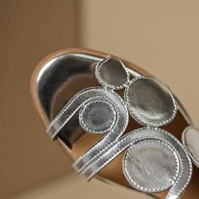 Close-up of a silver jewelry store sign with shiny circular and curved metal elements, representing elegant and stylish jewelry displays at Monalisa Medical.